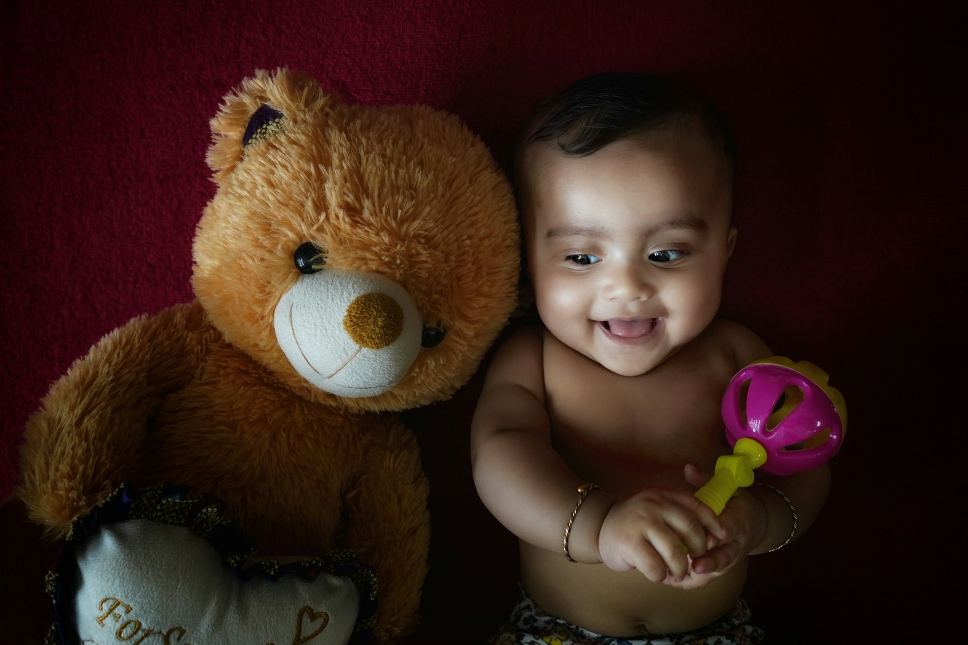 a baby sitting next to a teddy bear